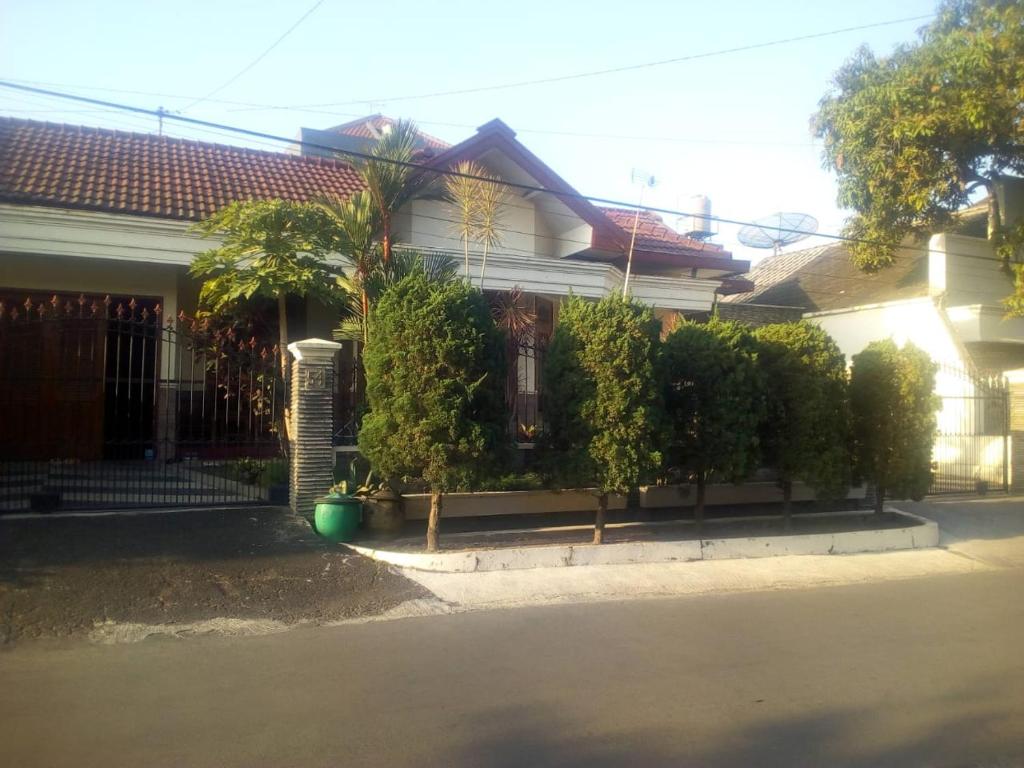 a house with a fence and trees in front of it at Nusin 54 Homestay in Malang
