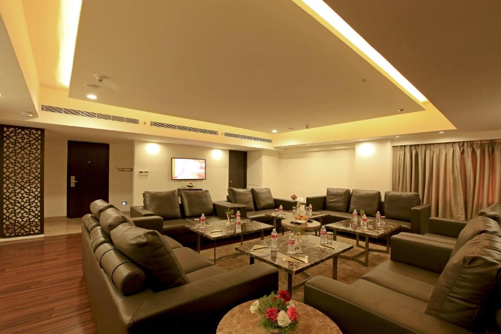 a living room with couches and tables and a television at Goutham Grand Hotel in Tenāli