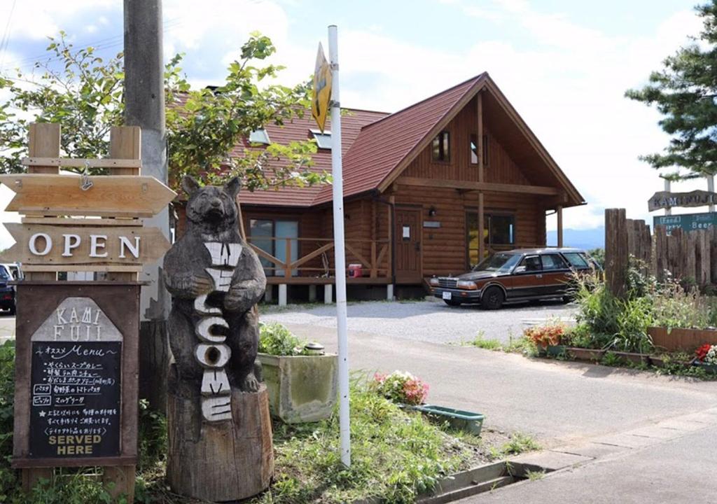 a teddy bear sitting on a sign in front of a house at Pension Kamifuji in Osaki