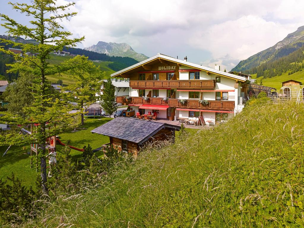 ein großes Haus auf einem Hügel auf einem Feld in der Unterkunft Appartementhaus Holiday in Lech am Arlberg