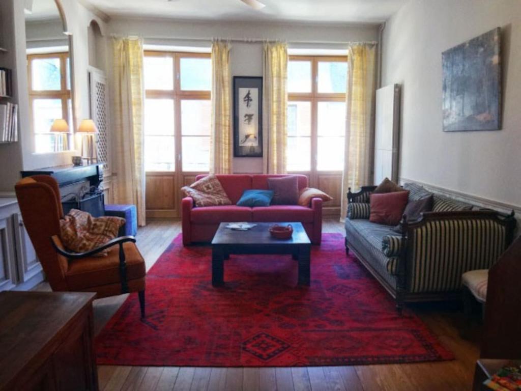 ein Wohnzimmer mit einem roten Sofa und einem roten Teppich in der Unterkunft Gîte de la Galerie du Pont in La Charité-sur-Loire