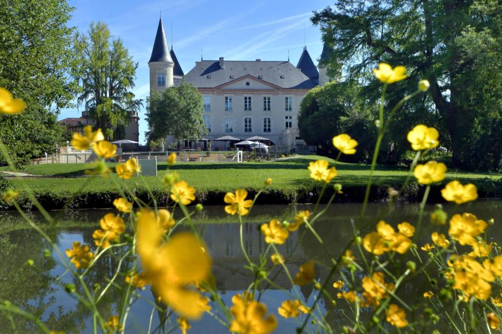 a building in the background with yellow flowers in the foreground at Logis Hotels - Château Saint Marcel in Boé