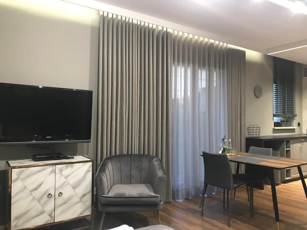 a living room with a television and a table and chairs at Apartament SUNTIME in Radom