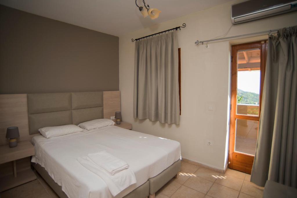 a bedroom with a white bed and a window at T'Aloni in Chortáta