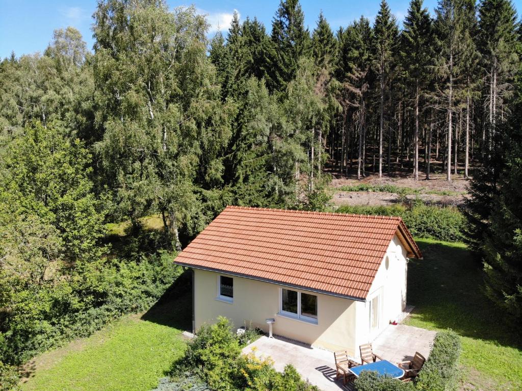 una pequeña casa blanca con techo rojo en Bungalow am Waldesrand/ Haus Konrad, en Suhl