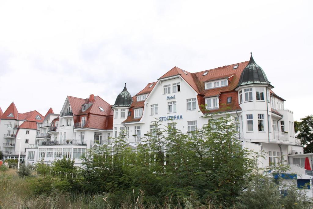 eine Reihe weißer Gebäude mit roten Dächern in der Unterkunft Hotel Stolteraa in Warnemünde