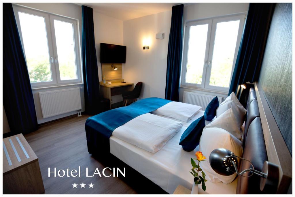 a hotel room with a bed and two windows at Hotel LACIN in Nuremberg