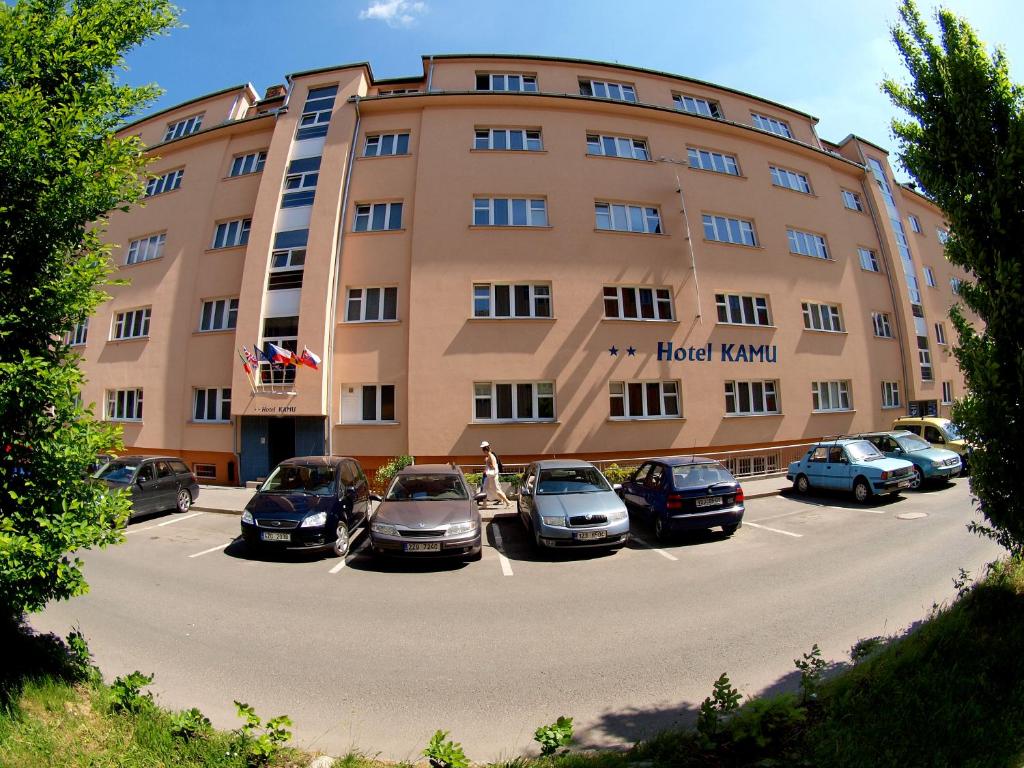 duży budynek z samochodami zaparkowanymi na parkingu w obiekcie Hotel KAMU GARNI w mieście Vsetín