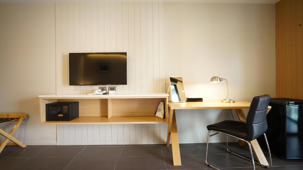 A room workspace with a desk, office chair, television, safe, and minibar.
