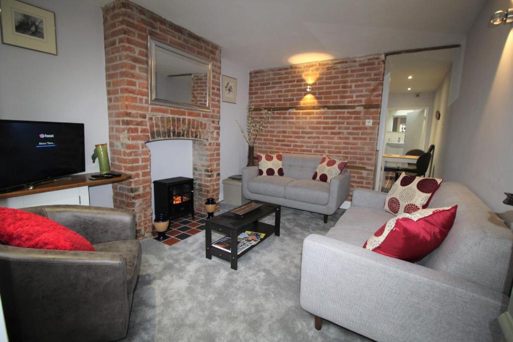 una sala de estar con 2 sofás y una pared de ladrillo en 1 Steam Packet Cottage en Canterbury