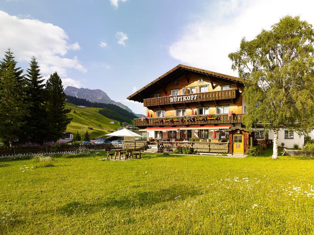 a large wooden building in a field of grass at Chalet Rüfikopf in Lech am Arlberg