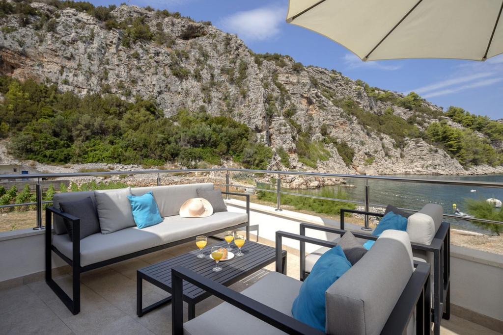 d'une terrasse avec un canapé et des chaises sur un balcon. dans l'établissement Robinson Agava, à Selca kod Bogomolja