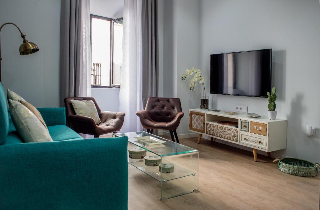 un salon avec un canapé bleu et une télévision dans l'établissement Apartamentos Turísticos Moret 11 - 1C, à Cáceres