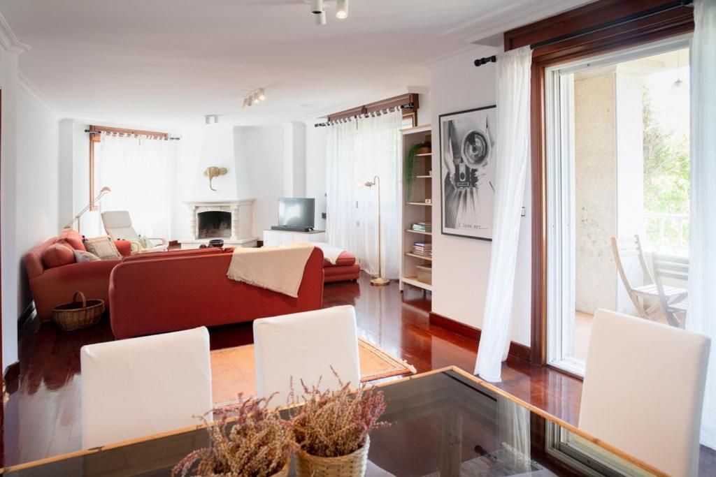 ein Wohnzimmer mit einem roten Sofa und weißen Stühlen in der Unterkunft Canido, Vigo, Rias Baixas in Oya