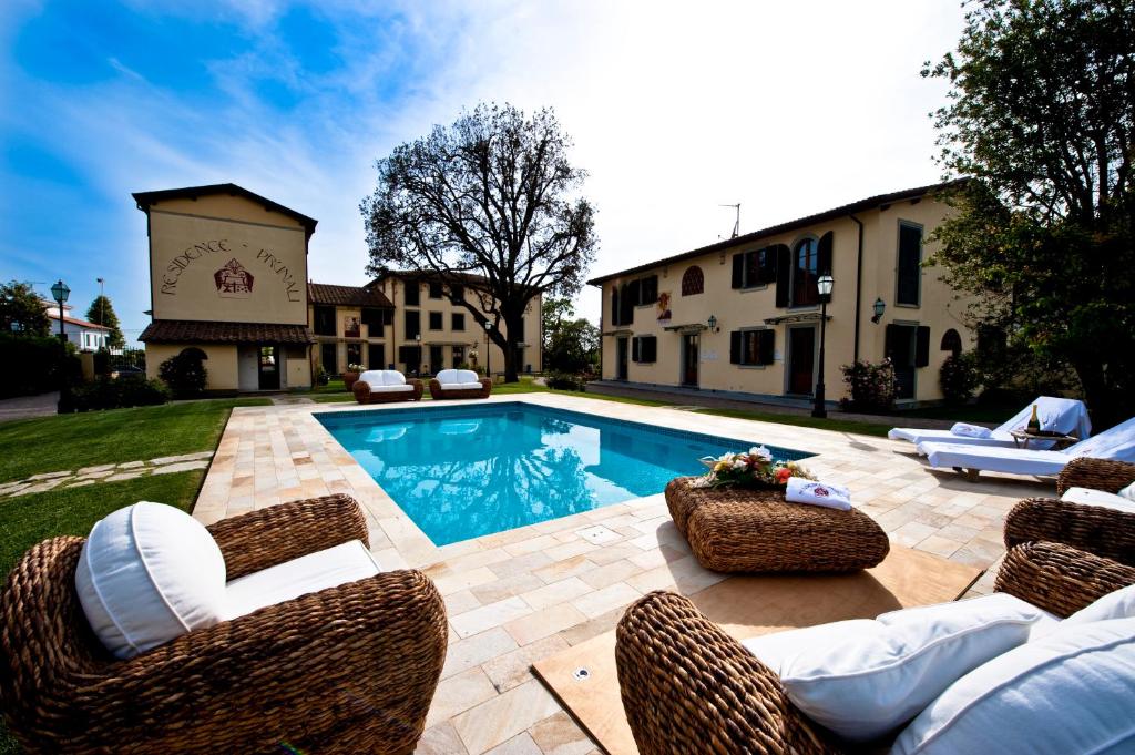un patio trasero con piscina y sillas de mimbre en Residence Prunali, en Massarosa