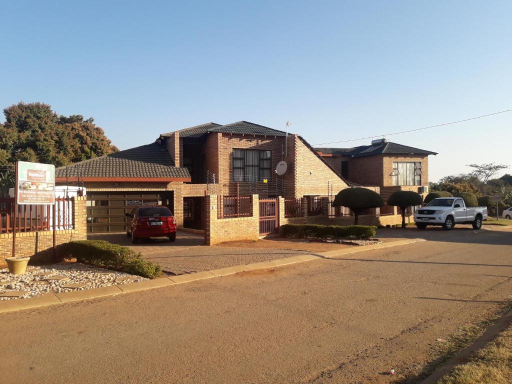 een bakstenen gebouw met een auto geparkeerd op een parkeerplaats bij Vakhusi Guesthouse in Malamulele