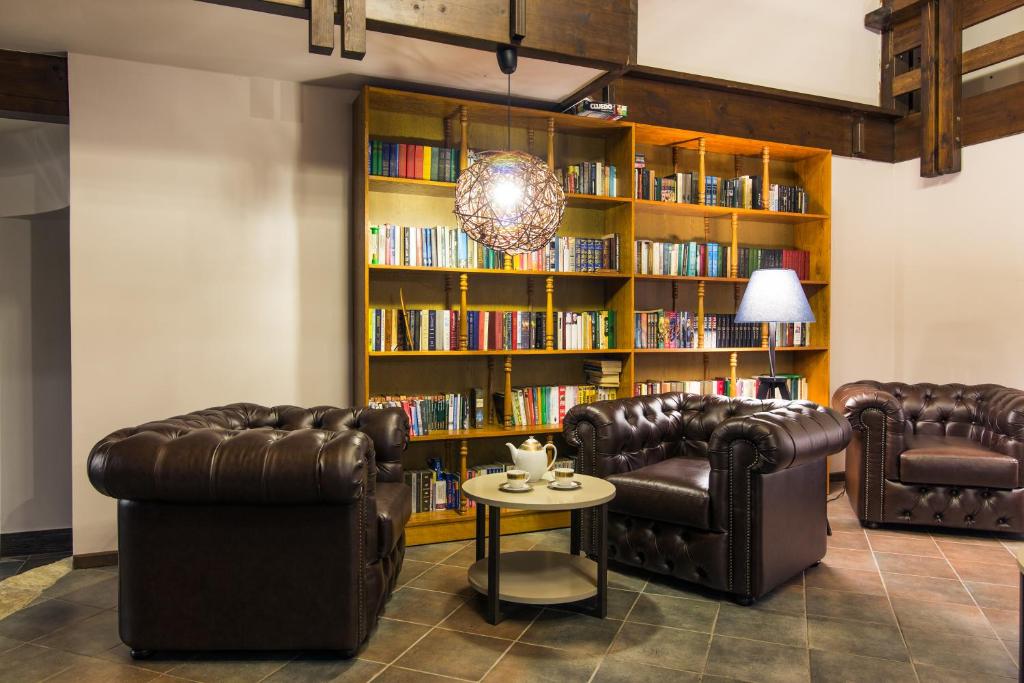 a library with leather chairs and a book shelf with books at Shalet Greystone in Estosadok