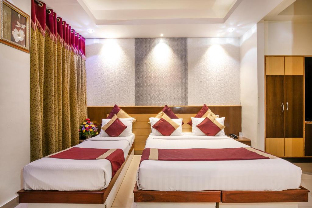 2 camas en una habitación de hotel con almohadas rojas y blancas en Aishwarya Residency, en Mysore