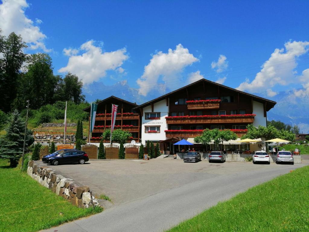 een groot gebouw met auto's geparkeerd op een parkeerplaats bij Hotel Restaurant Knobelboden in Oberterzen