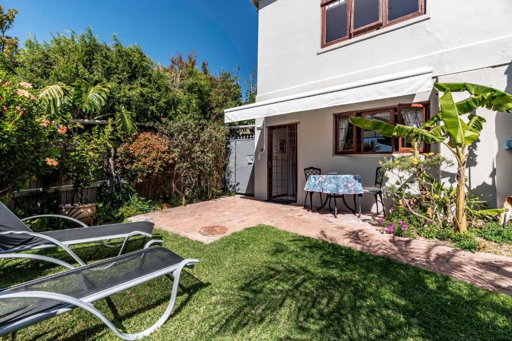 a patio with a table and chairs in a yard at Garden apartment Bay View in Cape Town