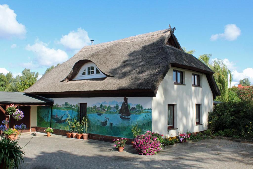 a house with a thatched roof with a painting on it at Zur Alten Boddenfischerei Ferienwohnung Zander in Neuendorf Heide