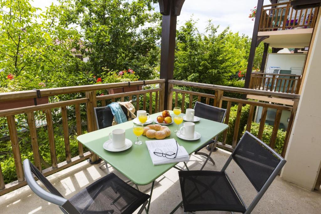 a table with a bowl of fruit on a balcony at Résidence Odalys Le Domaine des Rois in Bergheim