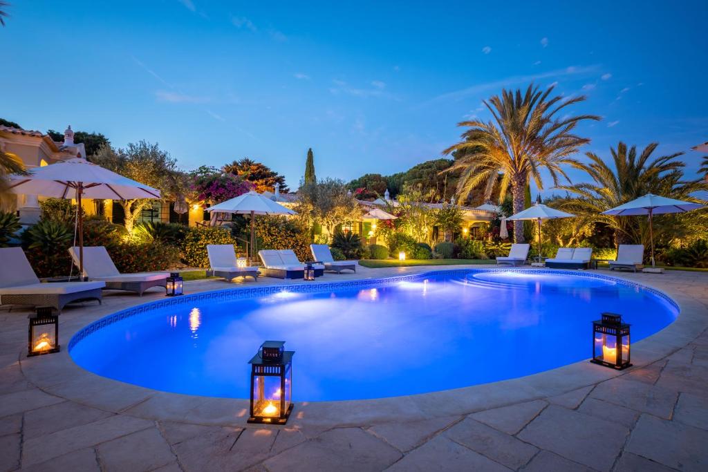 uma piscina com cadeiras e guarda-sóis à noite em Vila Balaia - Luxury Boutique Villas em Albufeira