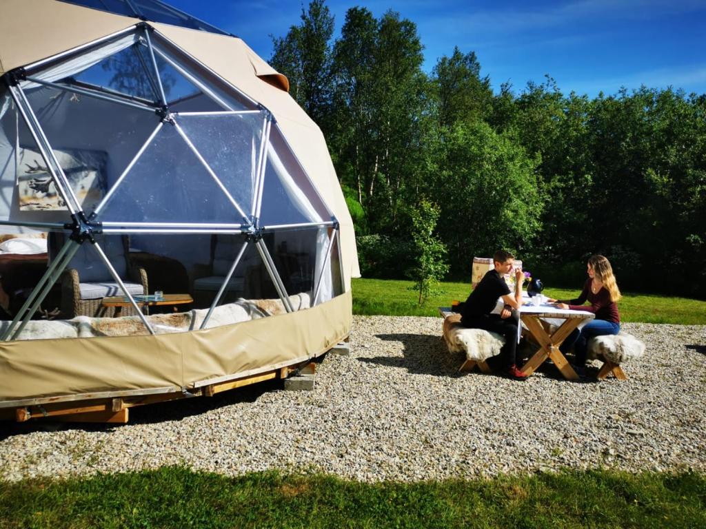 grupa ludzi siedzących przy stole w namiocie w obiekcie Wild Caribou Dome w mieście Lakselv