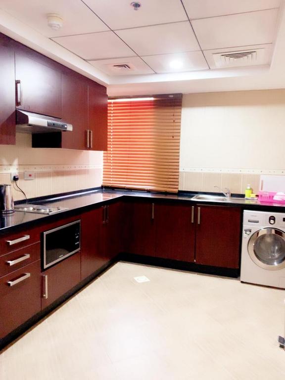 a large kitchen with brown cabinets and a dishwasher at Hala Inn Hotel Apartments - BAITHANS in Ajman 