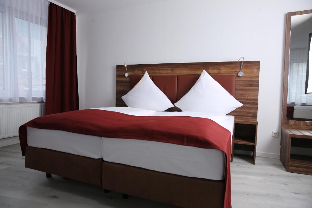 a bedroom with a large bed with red and white pillows at Hotel Grand Corner in Frankfurt