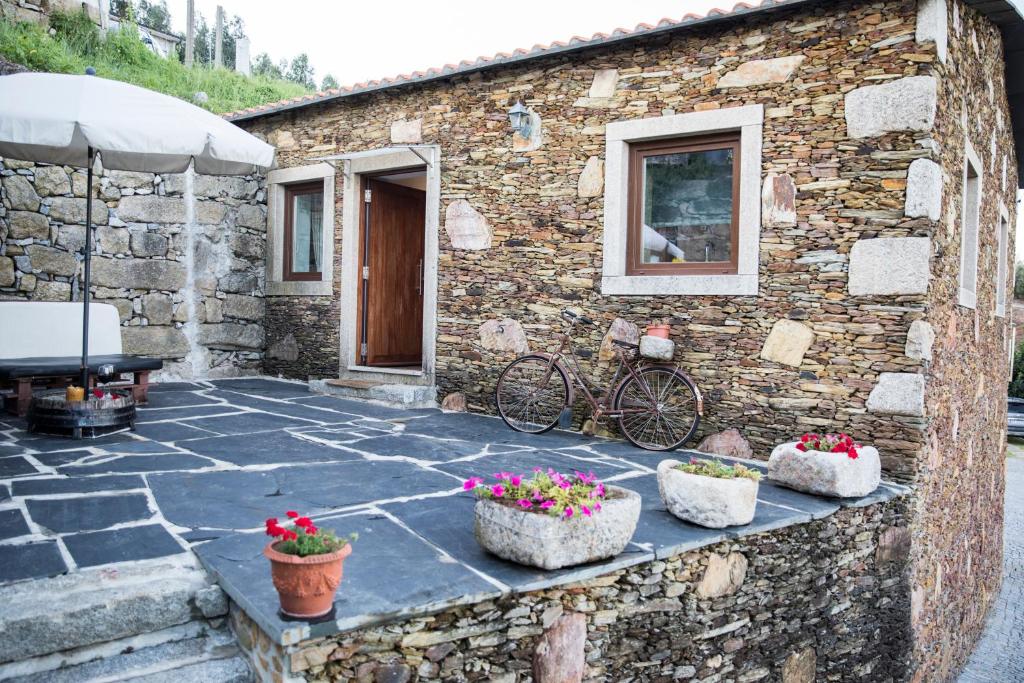 - un bâtiment en pierre avec une terrasse ornée de fleurs en pots dans l'établissement CASA DA CASADA VILLA RURAL - FOZ DO DOURO by LW, à Foz do Sousa