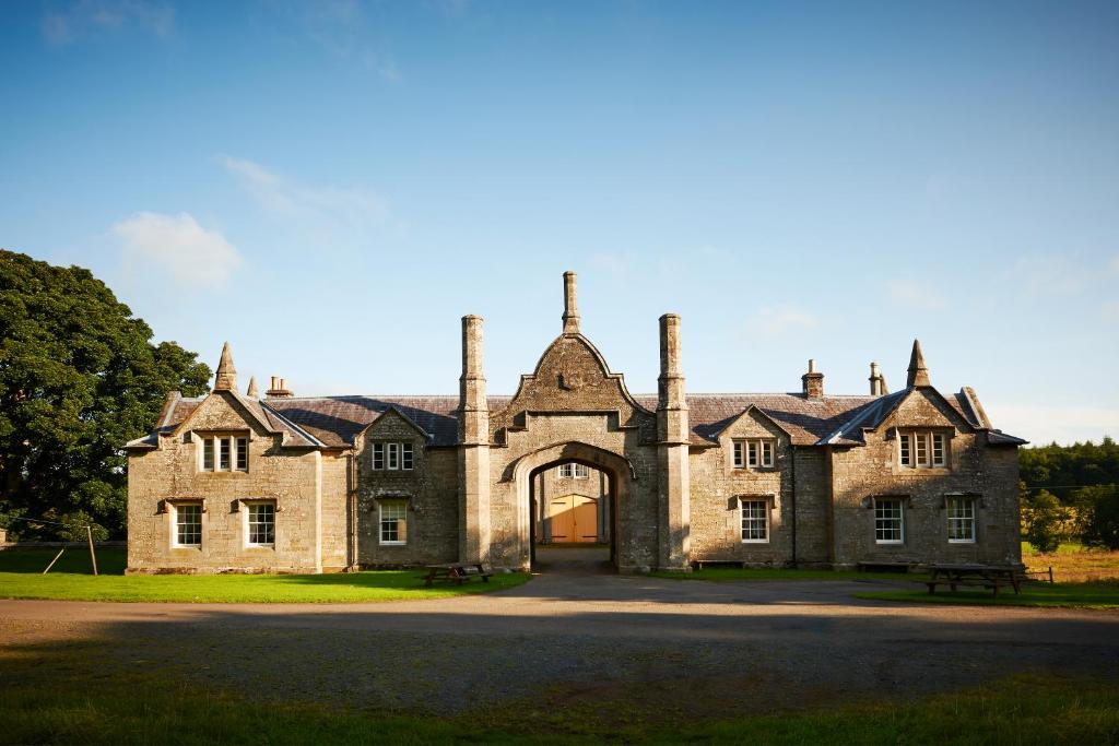 Maybole的住宿－Blairquhan Cottages，一座古老的石头房子,设有大门廊