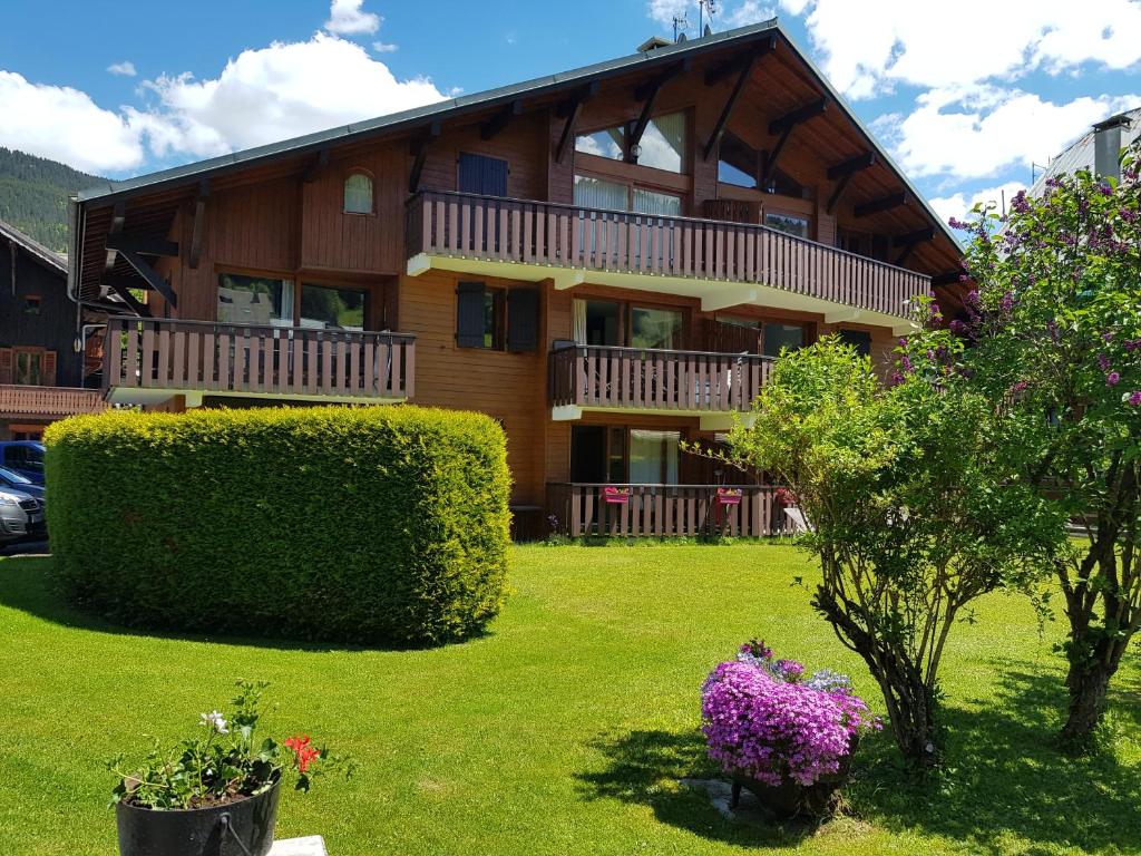 une grande maison en bois avec une cour ornée de plantes dans l'établissement Studio Le Marquis 2, à Morzine