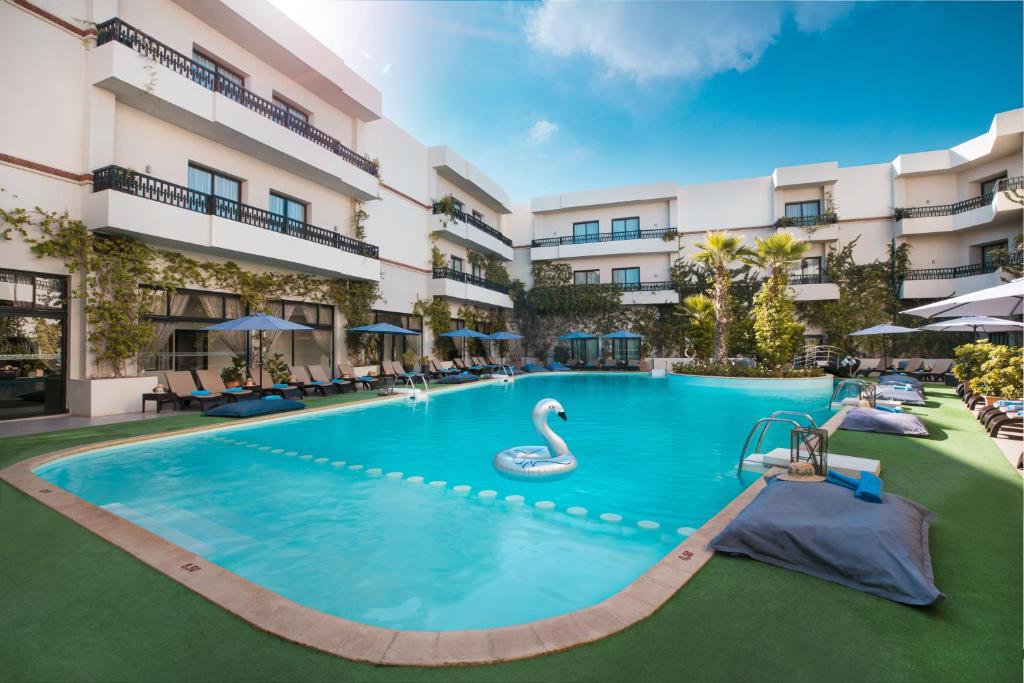 ein Schwimmbad in einem Hotel mit einem Schwan in der Mitte in der Unterkunft Kech Boutique Hotel & Spa in Marrakesch