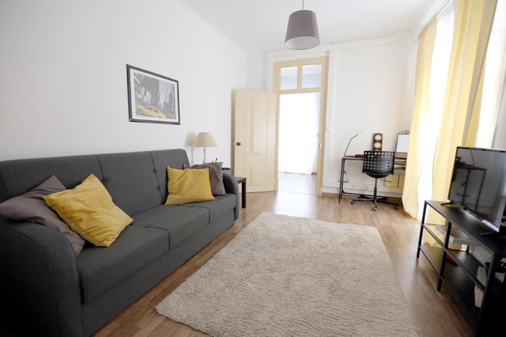 a living room with a gray couch and yellow pillows at Azeitão Village in Azeitao