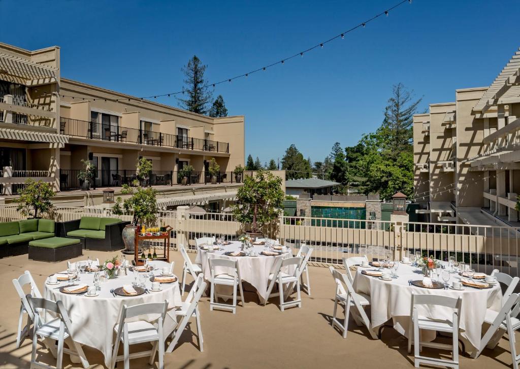 eine Gruppe von Tischen und Stühlen auf einer Terrasse in der Unterkunft Toll House Hotel Los Gatos in Los Gatos