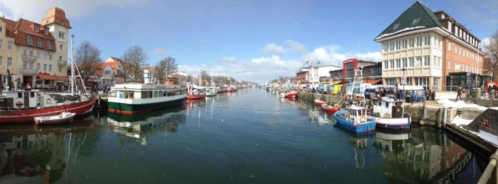 a group of boats docked in a canal with buildings at Doppelzimmer Zapfhahn, direkt am Alten Strom in Warnemünde