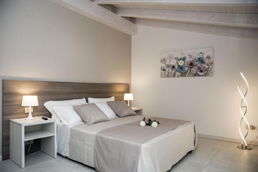 a white bedroom with a large bed and two lamps at Camelot Appartamenti - Business e Holiday in San Martino Buon Albergo