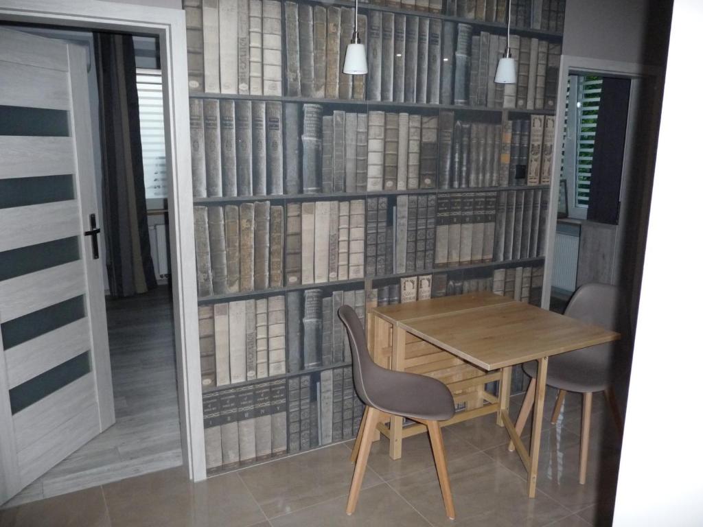 stół i krzesła przed ścianą książek w obiekcie Nordic Apartamenty Grochowa w mieście Białystok