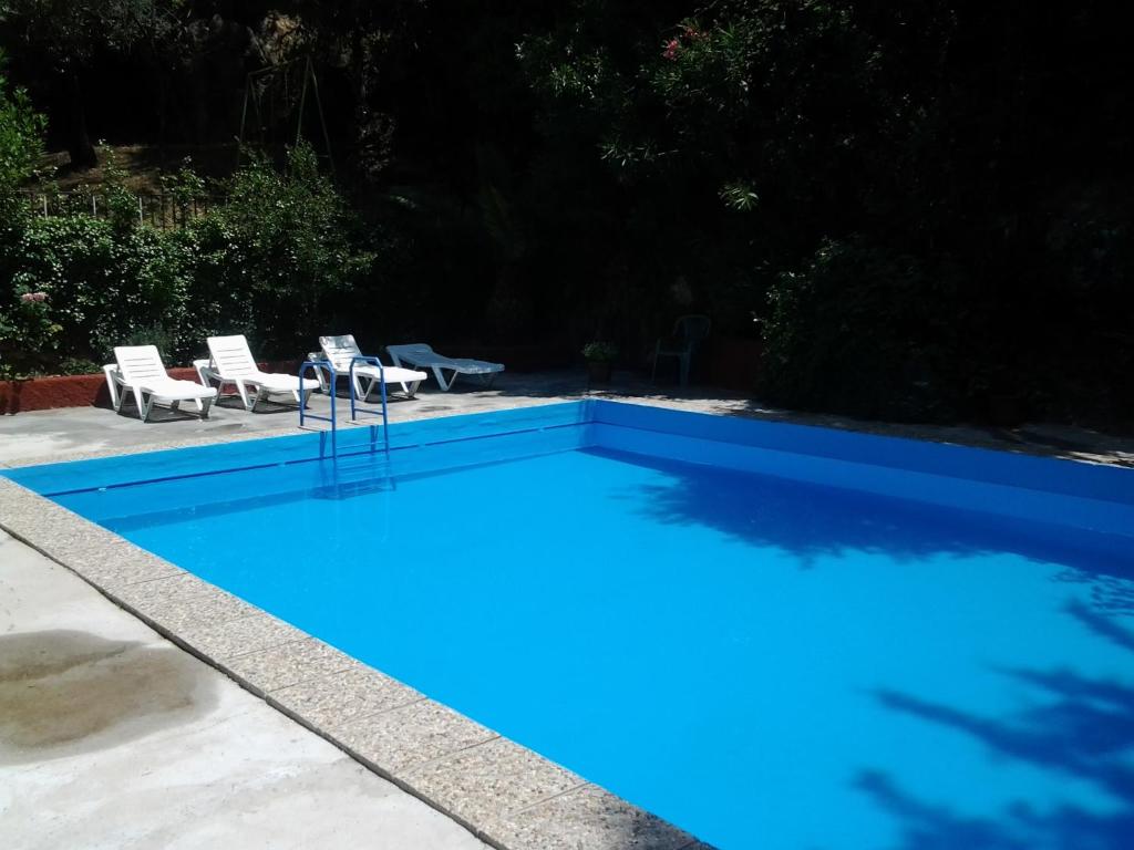 uma piscina azul com duas cadeiras e uma mesa em Casa Fuente De La Argamasa em Cazorla