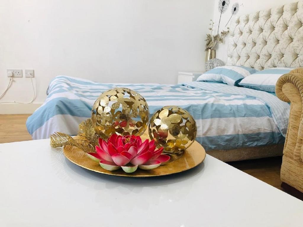 un plato con una flor en una mesa junto a una cama en Lux Apartment in Gatwick, en Crawley