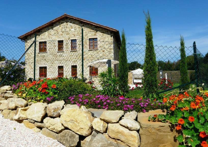 a stone house with flowers in front of a fence at B&B Monticelli in Gubbio