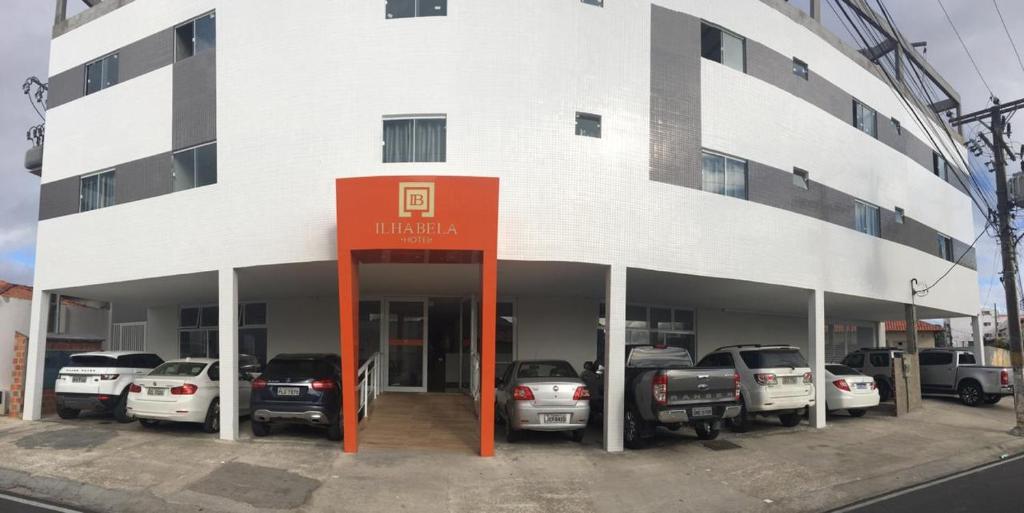 a building with cars parked in a parking lot at Ilha Bela Hotel in Paulo Afonso