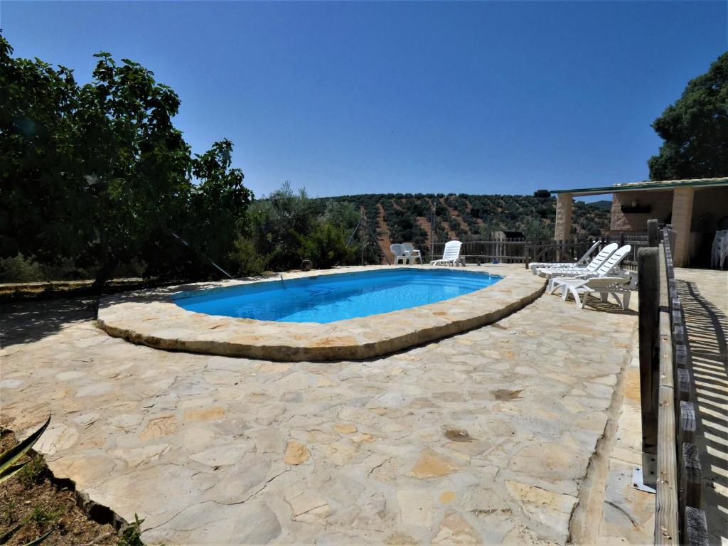 a swimming pool in a yard with two chairs around it at Casa Rural Brigido in Villanueva de Tapia