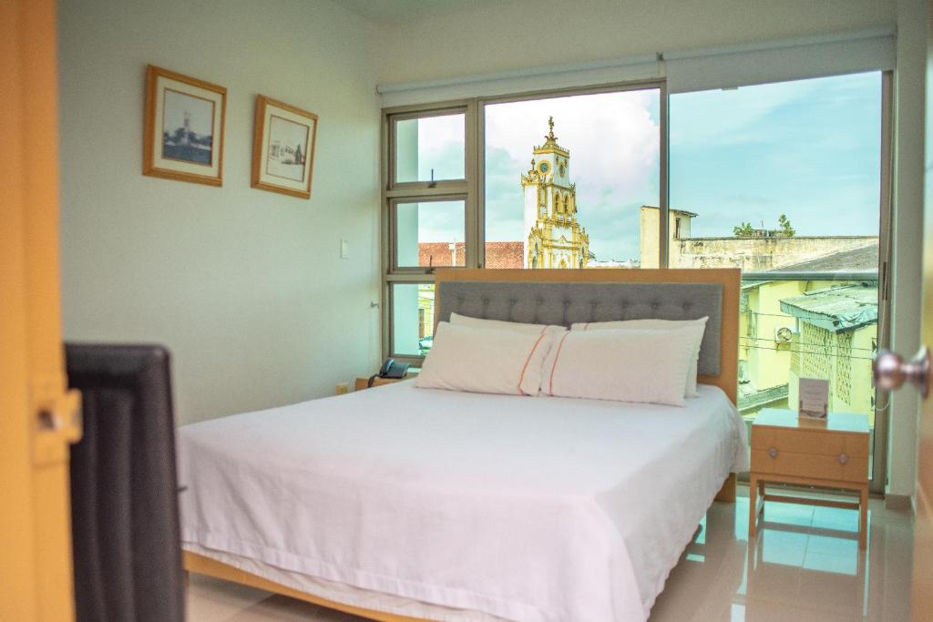 Un dormitorio con una cama y una ventana con una torre de reloj. en Onoma Hotel, en Lorica