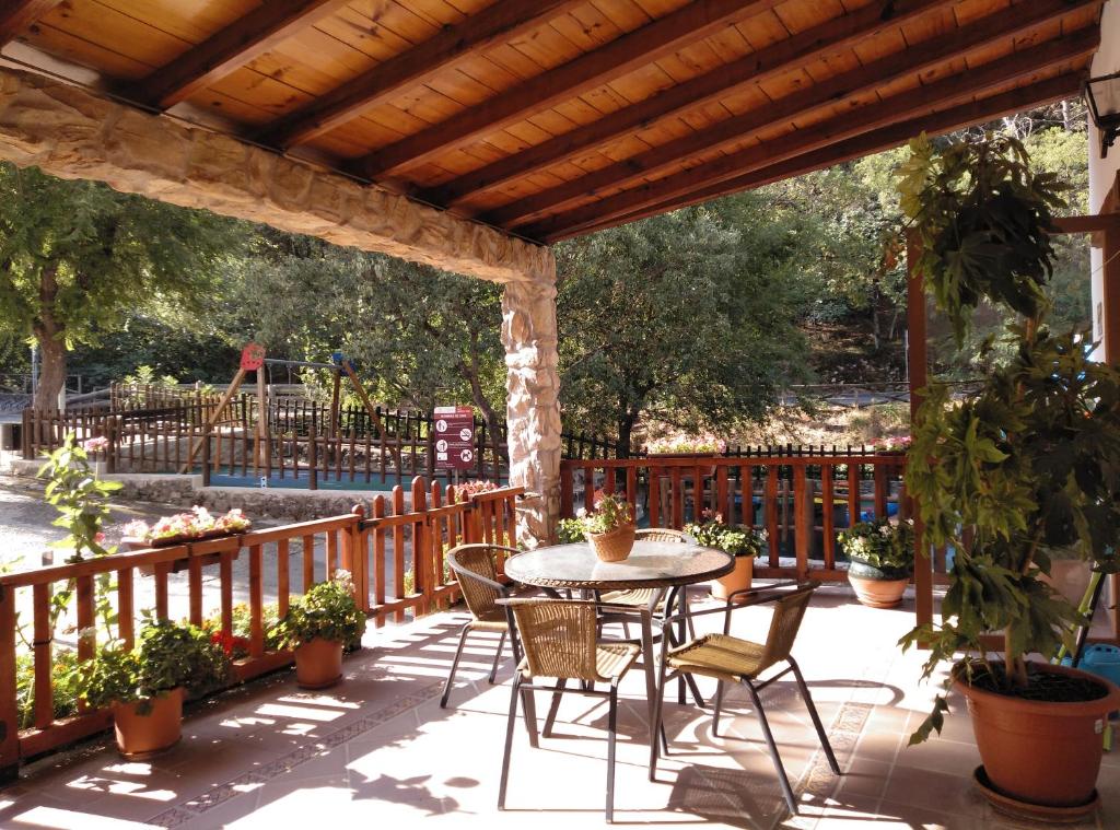 a patio with a table and chairs under a wooden pergola at Casa Rural El Tejo in Arroyo Frio