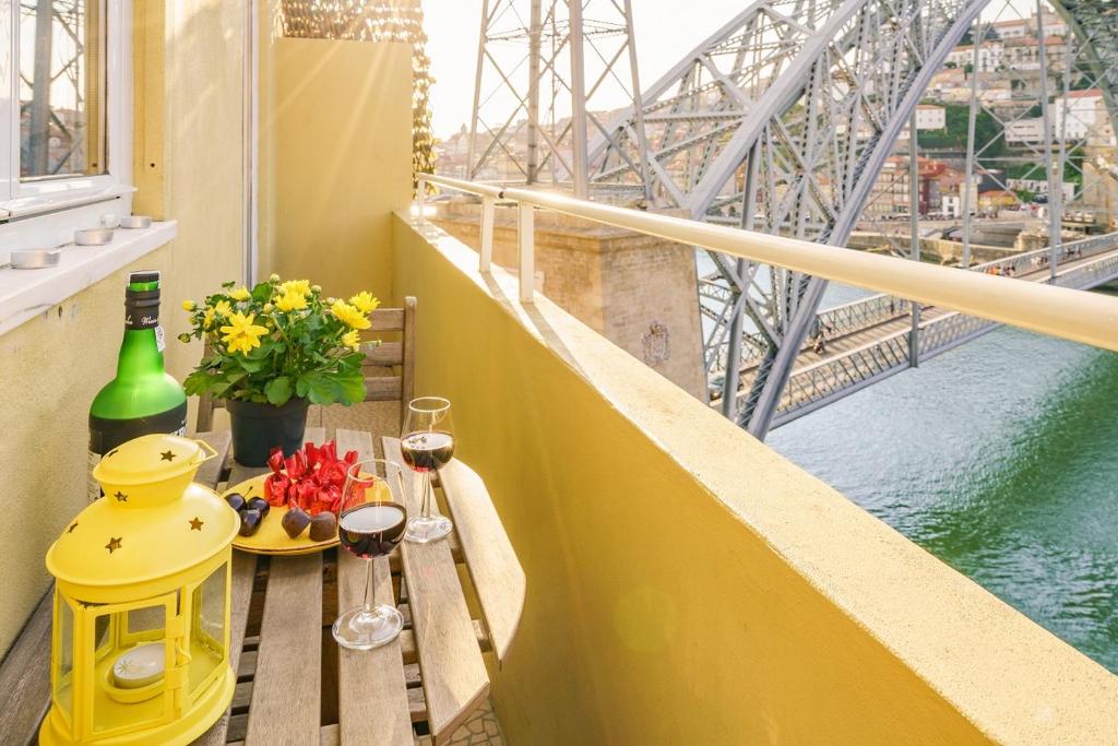 een balkon met een tafel met wijnglazen en een brug bij BestVillas Casa do Rio in Vila Nova de Gaia