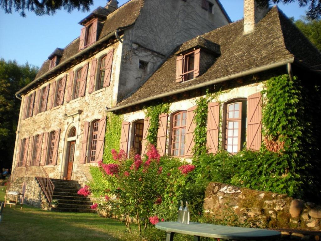 ein altes Steinhaus mit Blumen davor in der Unterkunft Chambres d'hôtes de charme Le Pradel in Monceaux-sur-Dordogne