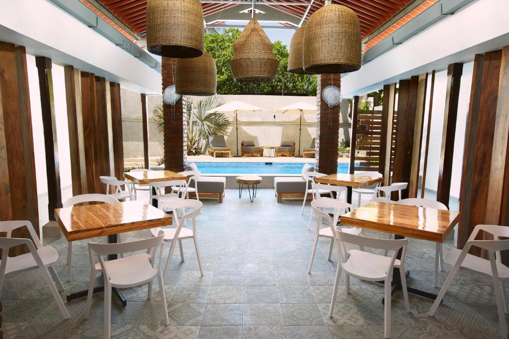a restaurant with tables and chairs and a pool at Villavela Hotel Boutique in Sonsonate
