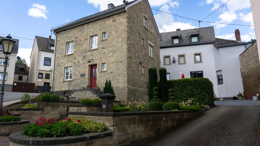 um edifício de tijolos com uma porta vermelha numa rua em Ferienhaus Alte Schule em Volkesfeld